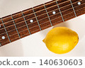 Acoustic guitar fretboard with steel strings and a whole yellow lemon 140630603