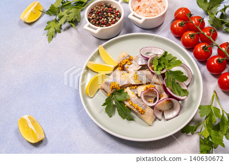 Pickled herring fillets on a plate with red onion and mustard seeds Pickled herring fillets on a plate with red onion and mustard seeds 140630672