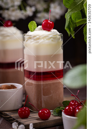 Layered chocolate parfait dessert with whipped cream and cherry Layered chocolate parfait dessert with whipped cream and cherry 140630709