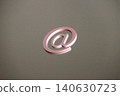A still life/internet communication concept featuring an "@" symbol clip against a metal plate background. 140630723
