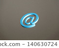 A still life/internet communication concept featuring an "@" symbol clip against a metal plate background. 140630724