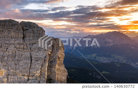Golden sunset light illuminates towering Dolomite rock formations beneath dark storm clouds. Atmospheric alpine landscape showcasing dramatic geology and mountain wilderness. Golden sunset light illuminates towering Dolomite rock formations beneath dark storm clouds. Atmospheric alpine landscape showcasing dramatic geology and mountain wilderness. 140630772