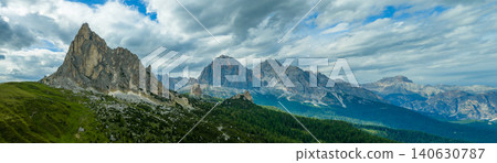 Dramatic panorama of Ra Gusela and Passo Giau beneath stormy clouds in the Italian Dolomites. Sunlit alpine meadows contrast with rugged limestone peaks and moody mountain scenery. Dramatic panorama of Ra Gusela and Passo Giau beneath stormy clouds in the Italian Dolomites. Sunlit alpine meadows contrast with rugged limestone peaks and moody mountain scenery. 140630787
