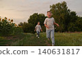 Happy children running in a summer field, Smiling boy and girl playing outdoors, Kids enjoying nature and fresh air, Siblings having fun together at sunset, Carefree childhood moments in the 140631817
