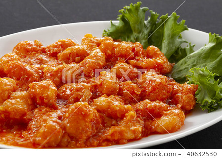 Freshly fried shrimp chili is served on a white plate, garnished with fresh lettuce for added color. Freshly fried shrimp chili is served on a white plate, garnished with fresh lettuce for added color. 140632530