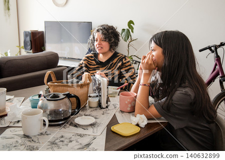 Mother and daughter are sitting at a table, one of them is wearing a striped shirt Mother and daughter are sitting at a table, one of them is wearing a striped shirt 140632899