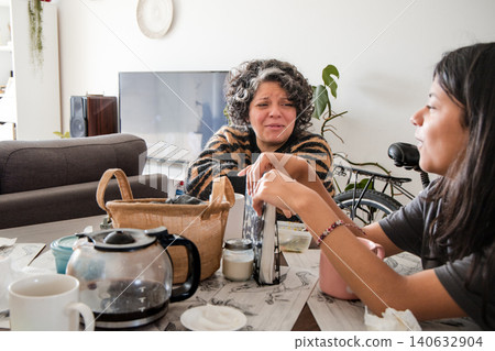 Mother and daughter are sitting at a table, one of them is wearing a striped shirt Mother and daughter are sitting at a table, one of them is wearing a striped shirt 140632904
