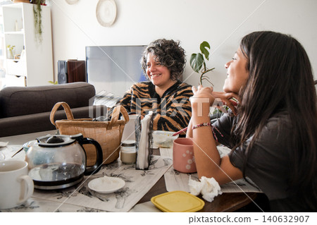 Mother and daughter are sitting at a table, one of them is wearing a striped shirt 140632907