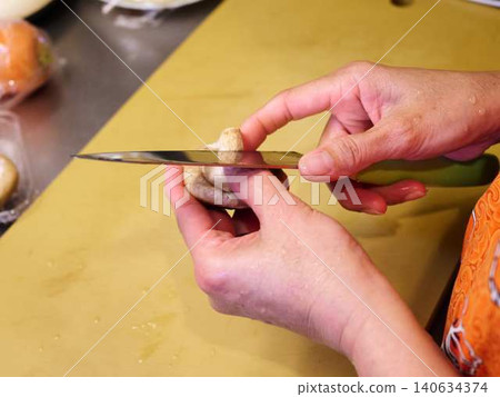 A woman cutting shiitake mushrooms with a kitchen knife. A woman cutting shiitake mushrooms with a kitchen knife. 140634374