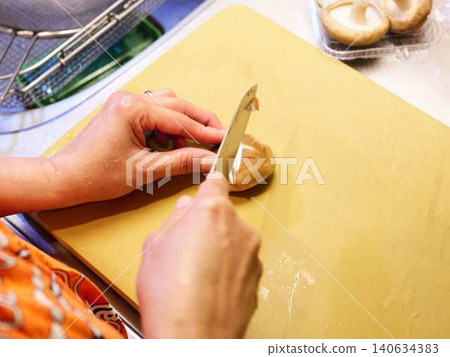 A woman cutting shiitake mushrooms with a kitchen knife. A woman cutting shiitake mushrooms with a kitchen knife. 140634383