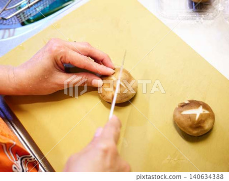 A woman cutting shiitake mushrooms with a kitchen knife. A woman cutting shiitake mushrooms with a kitchen knife. 140634388