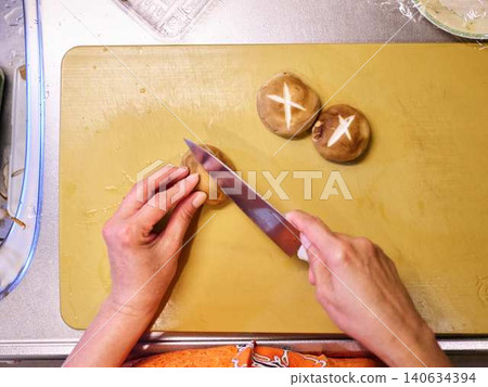 A woman cutting shiitake mushrooms with a kitchen knife. A woman cutting shiitake mushrooms with a kitchen knife. 140634394