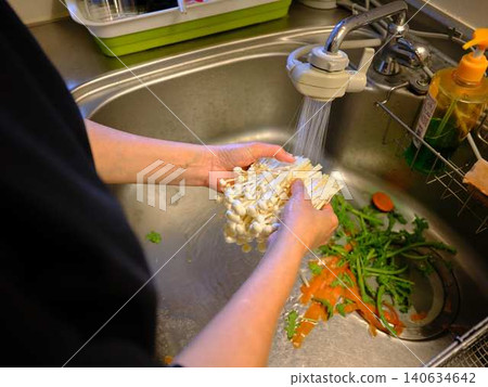 A woman washes enoki mushrooms. 140634642
