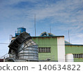 Looking up at the factory chimney and the blue sky. 140634822