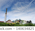 Looking up at the factory chimney and the blue sky. 140634825