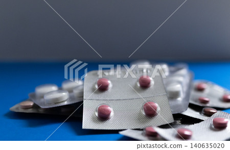 Medical drugs and pills in silver shiny package isolated on blue background Medical drugs and pills in silver shiny package isolated on blue background 140635020