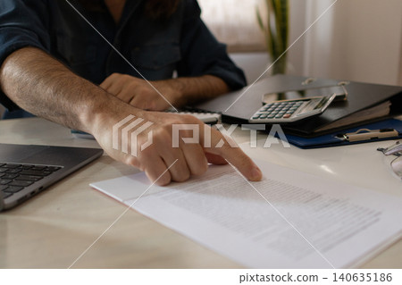 Close-up of the hands of an agent at his workplace explaining the contract to his client. 140635186