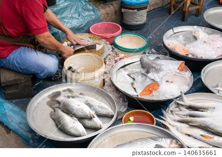 Fresh seafood displayed ice at local fish market while vendor prepares cleans fish highlighting traditional trade food supply daily commerce Fresh seafood displayed ice at local fish market while vendor prepares cleans fish highlighting traditional trade food supply daily commerce 140635661