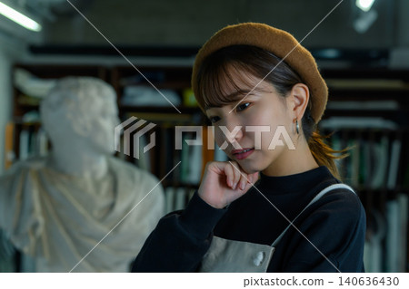 A young female artist contemplating in her studio. A young female artist contemplating in her studio. 140636430