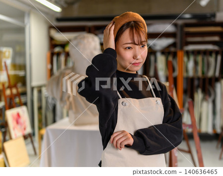 A female artist styling her hair in her studio. A female artist styling her hair in her studio. 140636465