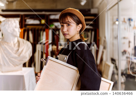 A woman holding a drawing board in an art room. A woman holding a drawing board in an art room. 140636466