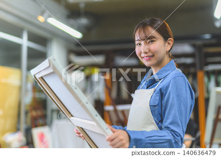 一位女藝術家手拿畫布，面帶微笑。 140636479
