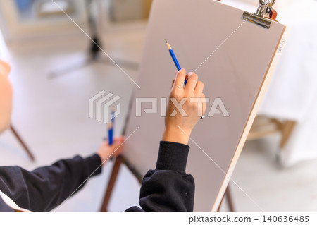 A woman drawing with a pencil at an easel. A woman drawing with a pencil at an easel. 140636485