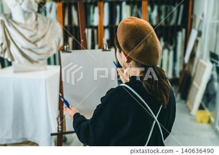 A woman's back as she sketches a plaster cast. A woman's back as she sketches a plaster cast. 140636490