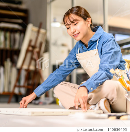 一位年輕女子正在她的工作室裡創作畫布作品。 140636493