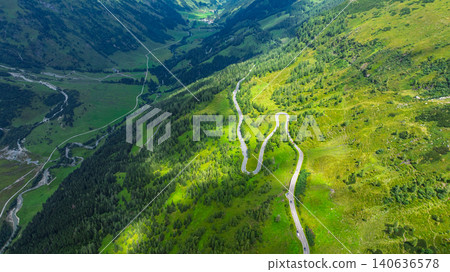 Aerial view of a winding mountain road through the lush green valley in the Austrian Alps area Aerial view of a winding mountain road through the lush green valley in the Austrian Alps area 140636578