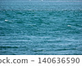 The blue surface of the water sparkles as it reflects the sunlight. 140636590