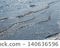 Waves crashing onto the shore and the water's surface sparkling in the sunlight. 140636596