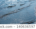 The waves lapping against the sandy beach and the sparkling reflection on the water's surface. 140636597