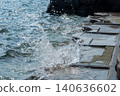 Large splashes of water violently crash against the steps of the seawall. 140636602