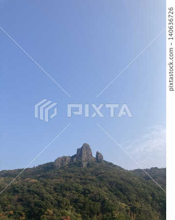 A rocky mountain towering on top of a mountain A rocky mountain towering on top of a mountain 140636726