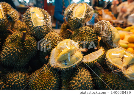 Fresh whole and cut durians wrapped in plastic for sale at a local market in Thailand 140638489