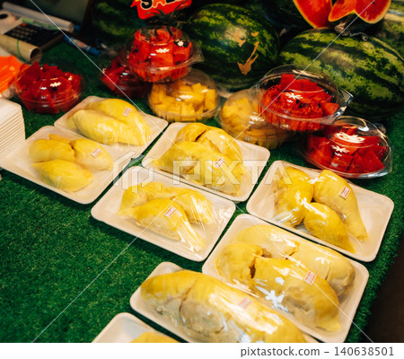 Fresh durian and sliced tropical fruits in plastic containers for sale at a Thai market Fresh durian and sliced tropical fruits in plastic containers for sale at a Thai market 140638501