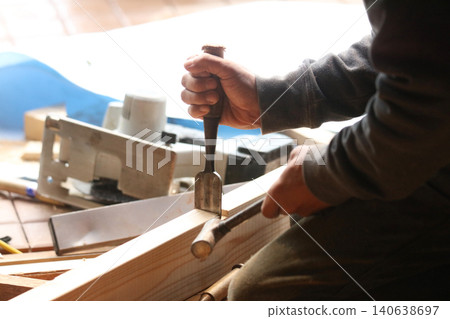 A man cutting wood with a chisel A man cutting wood with a chisel 140638697