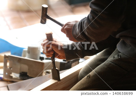 A man cutting wood with a chisel A man cutting wood with a chisel 140638699