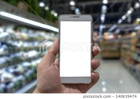 Hand holding smartphone with white blank screen over blurred supermarket and retail store in shopping mall interior background for product display montage. 140639474