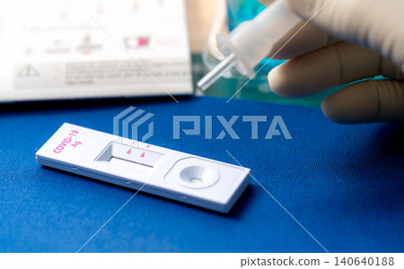 Hand holding sample tube and drops in the test device of covid 19 antigen self test. Antigen test kit for detection of coronavirus infection. Rapid antigen test. Coronavirus diagnosis. Medical device. Hand holding sample tube and drops in the test device of covid 19 antigen self test. Antigen test kit for detection of coronavirus infection. Rapid antigen test. Coronavirus diagnosis. Medical device. 140640188