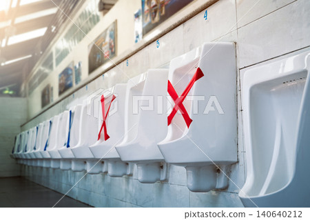 White ceramic urinals in men public toilet. Social distancing in men restroom to prevent coronavirus pandemic. Man bladder health with urinary incontinence problem. Urine infections. Male latrine WC. 140640212