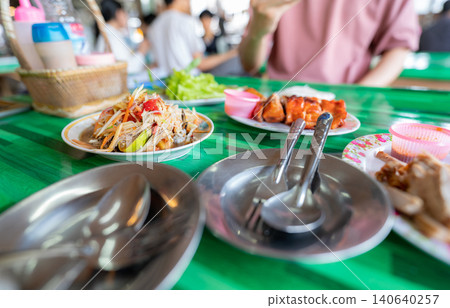Spicy green papaya salad or Som Tum with Thai rice noodles. Street food with hot and spicy dish in Thailand. The famous local Thai street food. Thai Esarn cuisine. Papaya salad with grilled chicken. Spicy green papaya salad or Som Tum with Thai rice noodles. Street food with hot and spicy dish in Thailand. The famous local Thai street food. Thai Esarn cuisine. Papaya salad with grilled chicken. 140640257