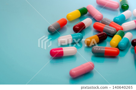 Antibiotic capsule pills on blue background. Prescription drugs. Colorful capsule pills. Antibiotic drug resistance concept. Pharmaceutical industry. Superbug problems. Medicament and pharmacology. 140640265
