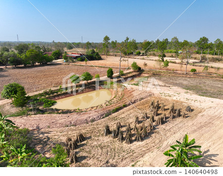 Drone view of rural farmland with irrigation pond, cassava harvest stacks and cultivated agricultural field during dry season, sustainable farming and countryside landscape. Sustainable land use. Drone view of rural farmland with irrigation pond, cassava harvest stacks and cultivated agricultural field during dry season, sustainable farming and countryside landscape. Sustainable land use. 140640498