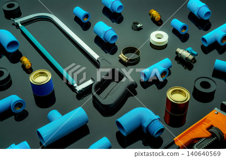 Plumbing tools. Plumber equipment. Blue PVC pipe fittings, hacksaw, glue can, and pipe wrench. House plumbing repair and maintenance service. DIY tools for plumbing work isolated on dark background. Plumbing tools. Plumber equipment. Blue PVC pipe fittings, hacksaw, glue can, and pipe wrench. House plumbing repair and maintenance service. DIY tools for plumbing work isolated on dark background. 140640569