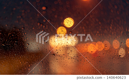 Orange night light bokeh from street light on traffic jam day. Rainy day. Transparent glass window with rain drop. Romantic weather. City life. Blur abstract background of urban light on rainy season Orange night light bokeh from street light on traffic jam day. Rainy day. Transparent glass window with rain drop. Romantic weather. City life. Blur abstract background of urban light on rainy season 140640623