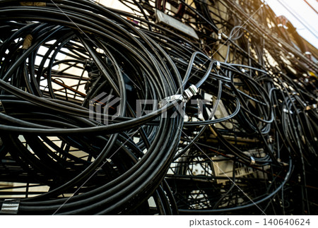 Tangled electrical wires on urban electric pole. Disorganized and messy to organization management concept. Closeup tangled electrical wires . Should take underground wire for beautiful landscape. Tangled electrical wires on urban electric pole. Disorganized and messy to organization management concept. Closeup tangled electrical wires . Should take underground wire for beautiful landscape. 140640624
