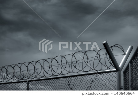 Prison security fence. Barbed wire security fence. Razor wire jail fence. Barrier border. Boundary security wall. Prison for arrest criminals or terrorists. Private area. Military zone concept. Prison security fence. Barbed wire security fence. Razor wire jail fence. Barrier border. Boundary security wall. Prison for arrest criminals or terrorists. Private area. Military zone concept. 140640664