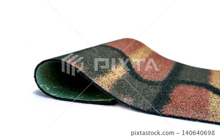 Dark green, yellow, and orange shingle roof on white background. Roofing material. Shingle roof texture. Shingle roof made from asphalt, plastic fiberglass. Rough unique pattern granules surface. 140640698